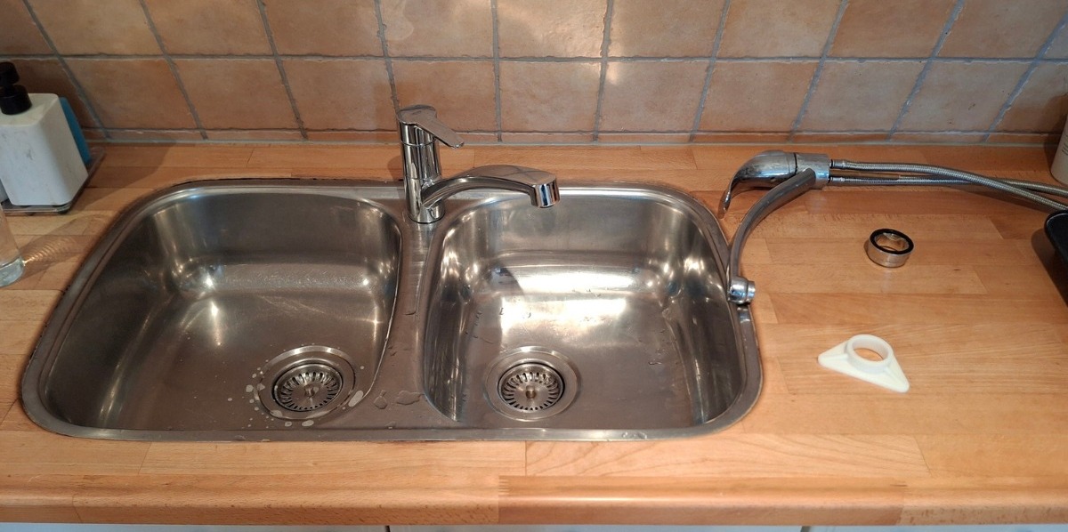 Rvs dubbele spoelbak met keukenkraan in een houten aanrecht