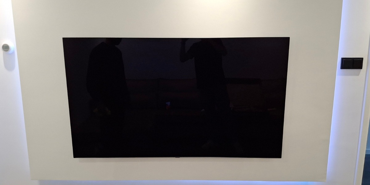 Tv aan de muur in een lichte nis met verlichting erachter